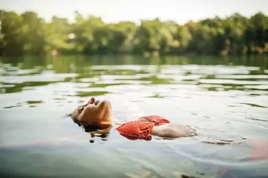 Woman on a holiday relaxing by swimming in lake. Woman in bikini floating in water facing up.
1093914580